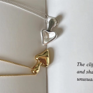 Close-up of gold and silver abstract mushroom pendants on thin chains over a book
