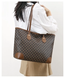 Detail of large tote bag with vintage monogram pattern and leather corner guards