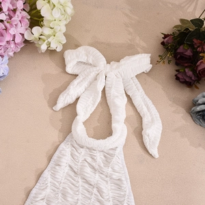 Close-up of white halter neck dress with ruched seersucker texture and floral decor