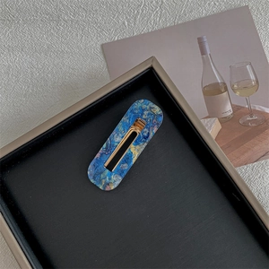 Close-up of a blue marble texture vintage hair clip on a black decorative tray