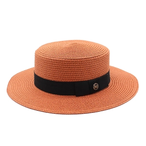 Détail d'un chapeau de paille avec ruban gros-grain noir et boucle dorée avec un M