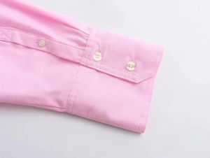 Detailed macro view of the pink cotton Oxford shirt cuff featuring two white resin buttons