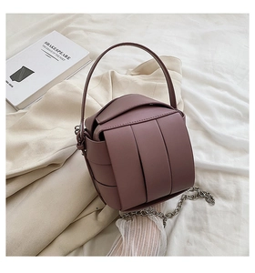 Close-up of a woven dark purple cylinder bag with silver chain and a hard handle