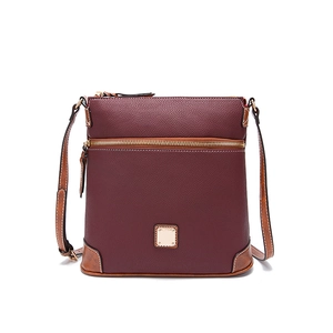 Detail of burgundy pebble leather texture and brown strap on a vintage crossbody bag