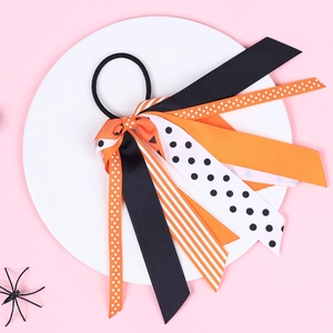 Halloween ribbon hair tie featuring orange and black polka dot patterns on a pink background