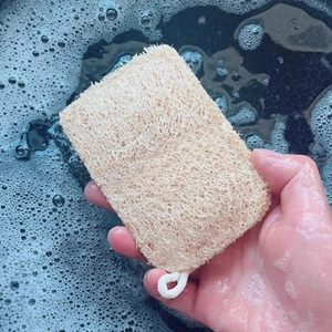 Natural loofah dishwashing sponge with fibrous texture being used in soapy kitchen water