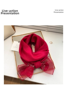 Detail of red silk wool scarf with gold lurex stripes on a gold tray with soft shadows