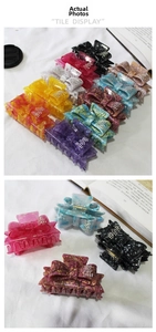 Detail showing various colors of rhinestone-studded butterfly hair claws on white fabric