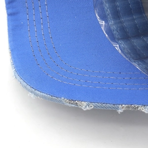 Detailed macro view of denim baseball cap brim with silver sequins and distressed edges