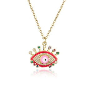 Macro detail of gold devil eye pendant with pink enamel and colorful zircon stones