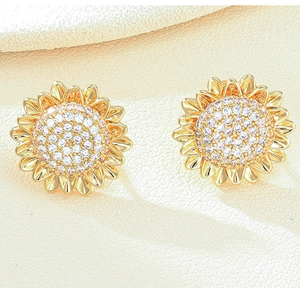 Close-up of gold sunflower stud earrings with shimmering clear cubic zirconia center