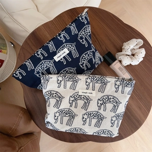 Flat lay of vintage sheep pattern canvas makeup bags on a wooden table with cosmetics