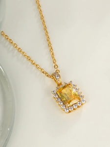 Detail of gold necklace with a square yellow gemstone pendant and zircon stones