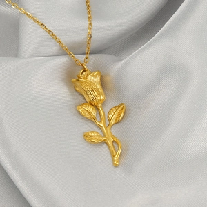 Close-up of golden rose pendant on silver silk fabric highlighting intricate metal details
