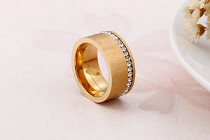 Dettaglio di un anello largo dorato con finitura opaca spazzolata e pavé di zirconi