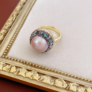 Macro view of pink pearl and colorful abalone shell inlay on golden vintage ring