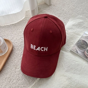 Close-up of burgundy cotton baseball cap featuring high-quality white BEACH embroidery