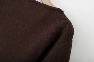 Macro detail of dark brown knitwear neckline and fine stitching on a wooden hanger