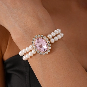 Close-up of double-row pearl bracelet with oval pink gemstone and diamond-set halo