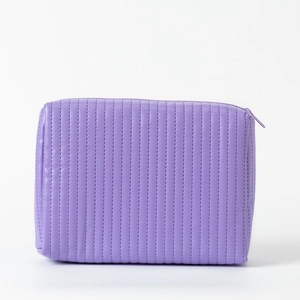 Detail of light purple quilted makeup bag featuring vertical lines and smooth zipper