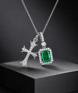 Detalle del colgante de cruz de plata y piedra verde esmeralda con halo de diamantes