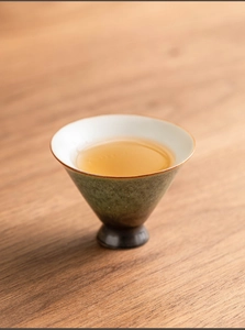 Detail of vintage green ceramic teacup with white interior and rustic kiln-changed glaze
