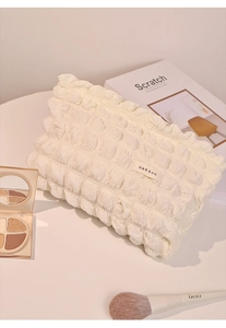 Neceser color crema con textura de burbujas y etiqueta sobre fondo blanco limpio