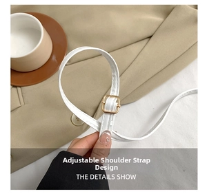 Detail shot of a white adjustable faux leather shoulder strap with a gold metal buckle