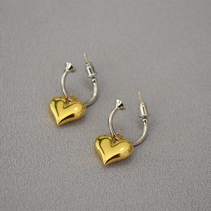Detail of two-tone heart drop earrings featuring gold heart pendant and silver hook
