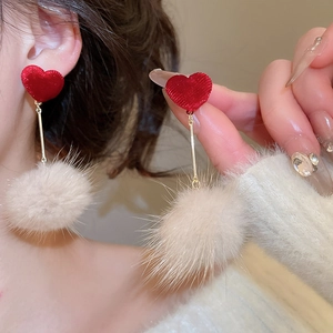 Détail de boucles d'oreilles cœur en tissu et pompon blanc cassé pour femmes