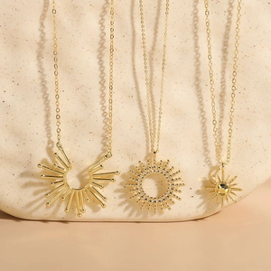 Detailed view of three 14K gold plated sun and starburst pendants on stone texture