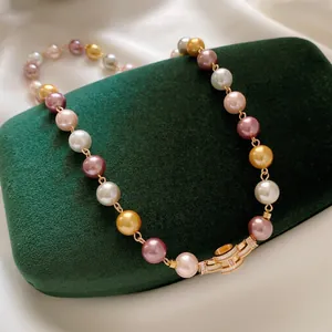 Elegant multi-color pearl necklace featuring a gold H-shaped zirconia clasp on green velvet