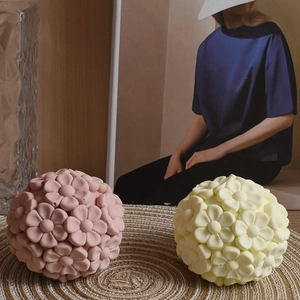 Detail of pink and yellow sphere-shaped floral scented candles on a woven coaster