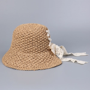 Detail of the woven straw hat featuring an elegant white lace ribbon and delicate texture