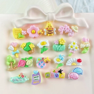 Colorful resin charms for DIY nail art and jewelry, including bees and flowers on a tray