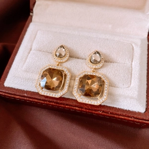 Macro detail of vintage gold drop earrings with square amber zircon and crystal accents