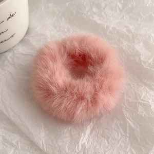 Nahaufnahme von weichem rosa Plüsch-Haargummi mit flauschiger Textur auf weißem Papier