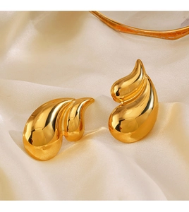 Macro shot of 18K gold-plated teardrop earrings on beige silk fabric with smooth finish