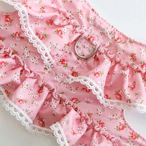 Detailed macro view of pink floral pet harness with lace trim and metal D-ring attachment