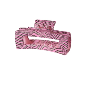 Close-up of a pink large hair claw clip with black wave pattern on a white backdrop