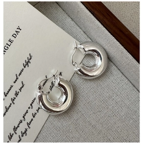 Gros plan de boucles d'oreilles créoles minimalistes en argent S925 sur fond gris