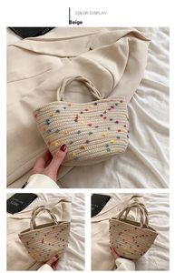 Close-up of beige woven straw bucket bag with colorful pom-pom details and dual top handles