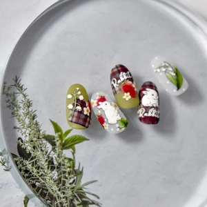 Détail de stickers à ongles gaufrés avec motifs de lapin et fleurs sur un plateau