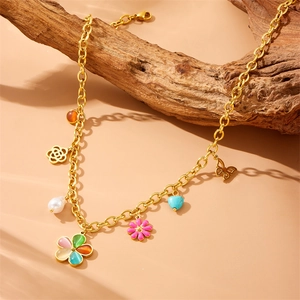 Gold chunky chain necklace with multi-element floral pendants and pearls on a wood branch