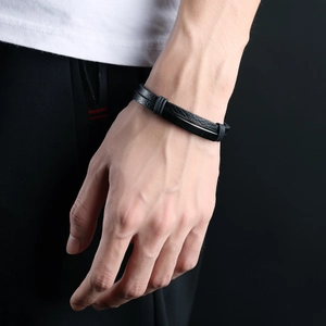 Men's double-layered black leather bracelet with metal accents on a model's wrist