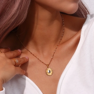 Detail of golden sunflower pendant necklace with water wave chain on a female model