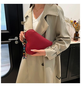 Detail of red heart-shaped leather bag with LOVE printed wide shoulder strap