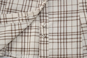 Detail of plaid shirt buttons and woven fabric texture in beige and brown tones