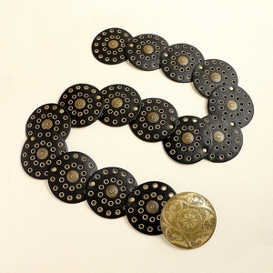 Detailed macro view of black round leather panels with bronze metal studs and buckle