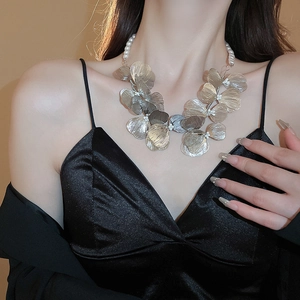 Detailed view of layered metallic flower petals with pearls on an elegant necklace